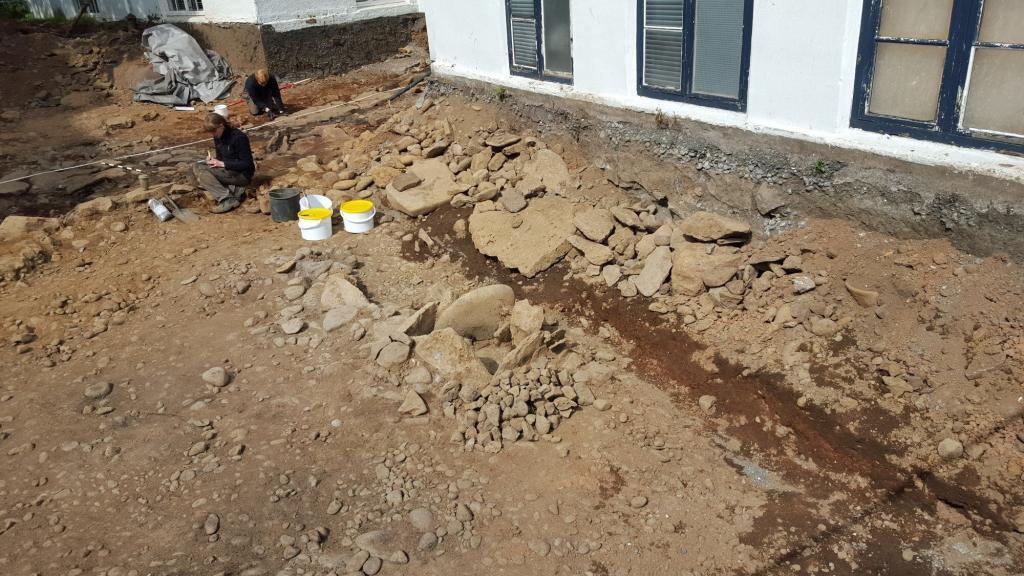 In the center of the image is the outdoor pot. The hearth is where the archaeologist is working. 