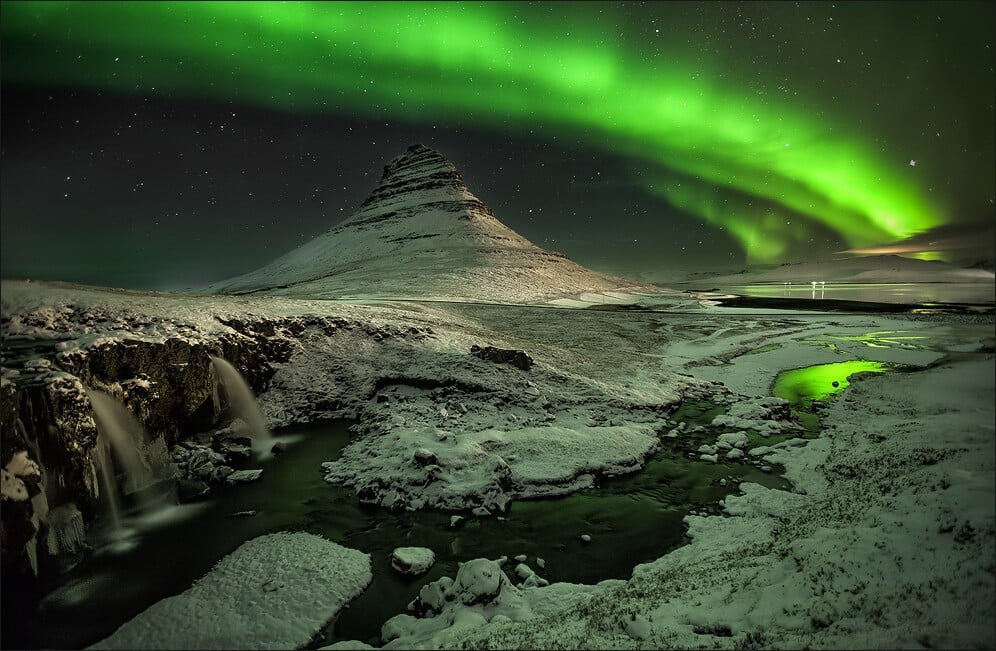 Kirkjufell with the northern lights in Iceland dancing in the winter sky. Photo by Martin Schulz who has created the ultimate guide to how to photograph Iceland.