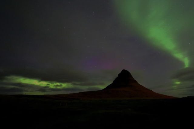 Kirkjufell mountain illuminated by the Icelandic northern lights.