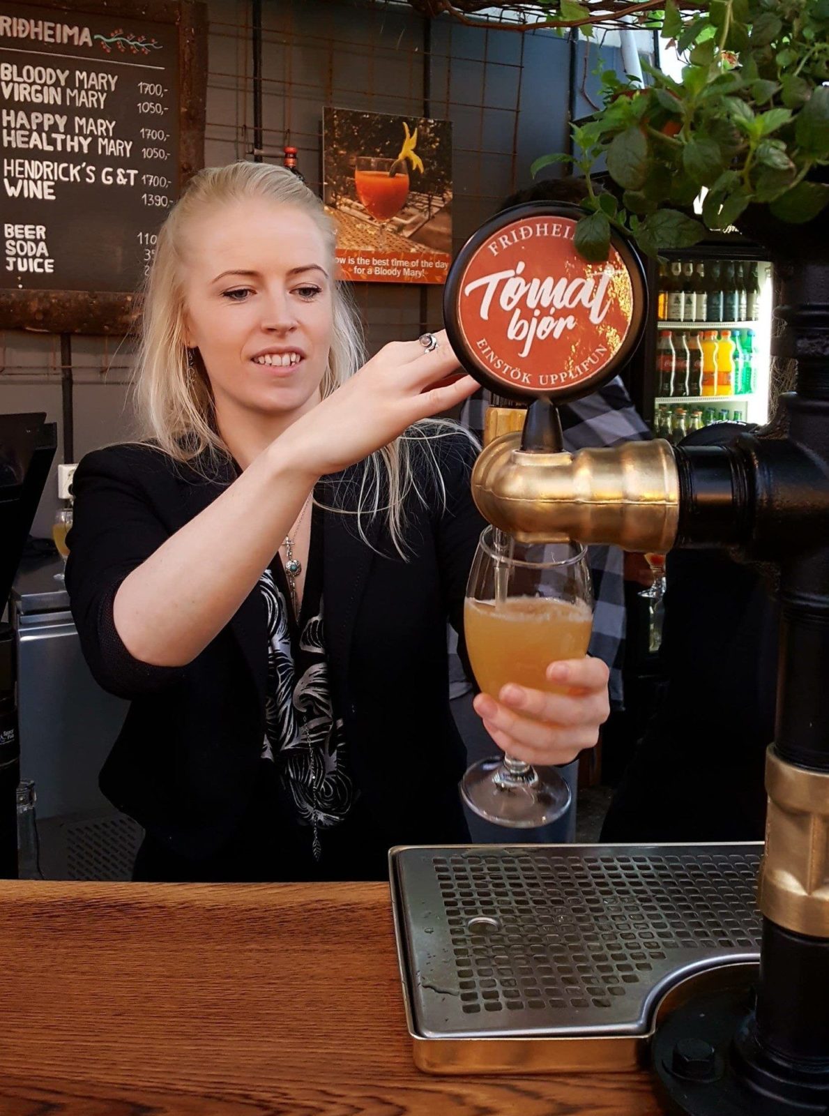 A woman pours tomato beer at Friðheimar restaurant which is on the Golden Circle in Iceland.
