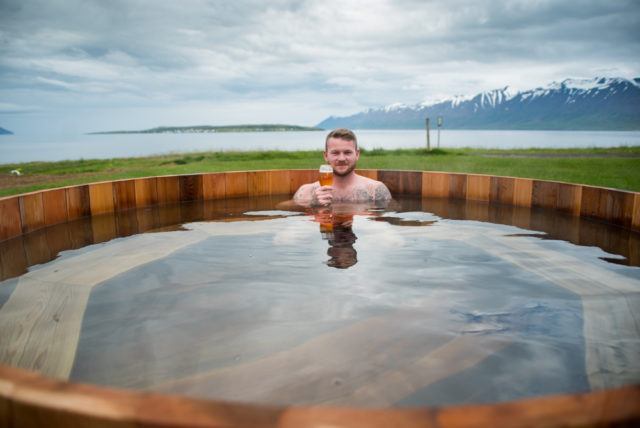 Man in a hot tub with a beer at the beer spa in Iceland. 