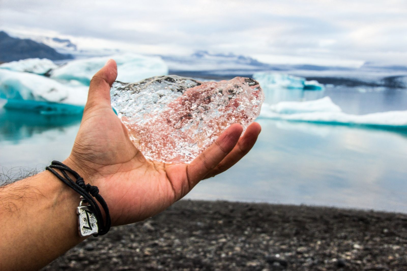 Hand with a piece of ice at the Breidamerkursandur beach in Icelandþ