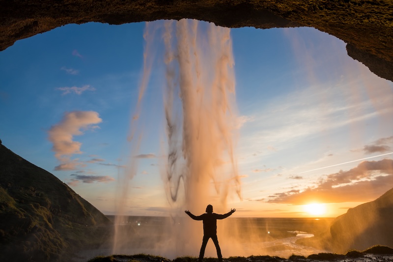 Standing behind the beautiful Seljalandsfoss waterfall on the south coast of Iceland in the twilight.